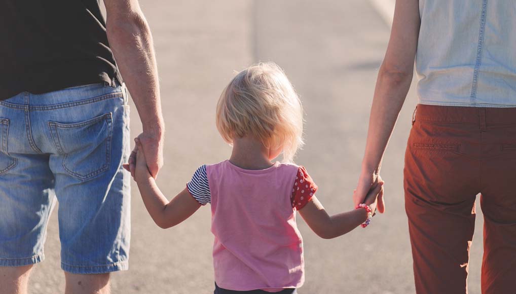 bambina con due adulti per mano